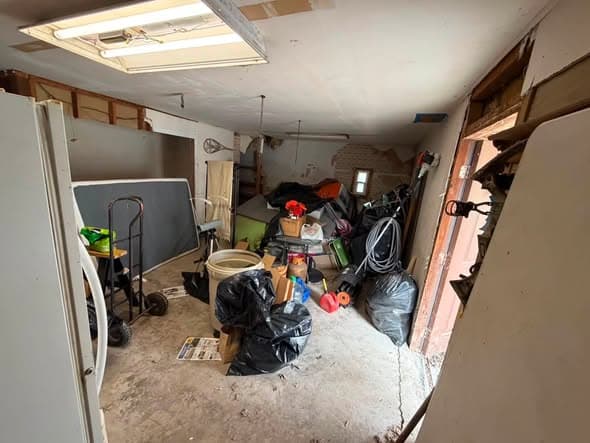 Garage packed with trash bags and buckets before a full cleanout