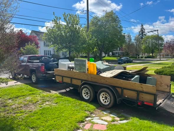 Midlakes Junk Removal truck and trailer loaded with household junk in a Finger Lakes driveway